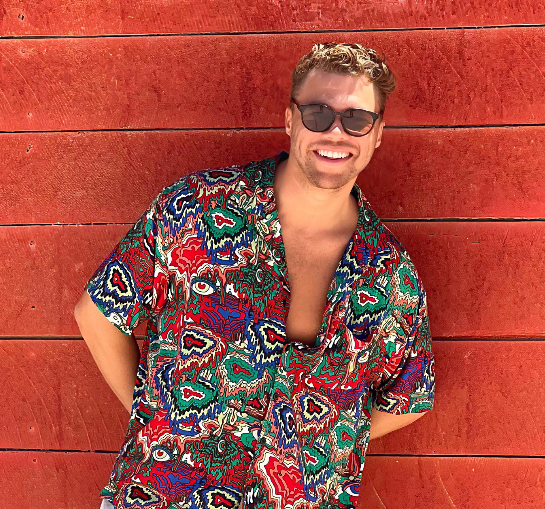 Kill Them With Colour in sunglasses against a red wall